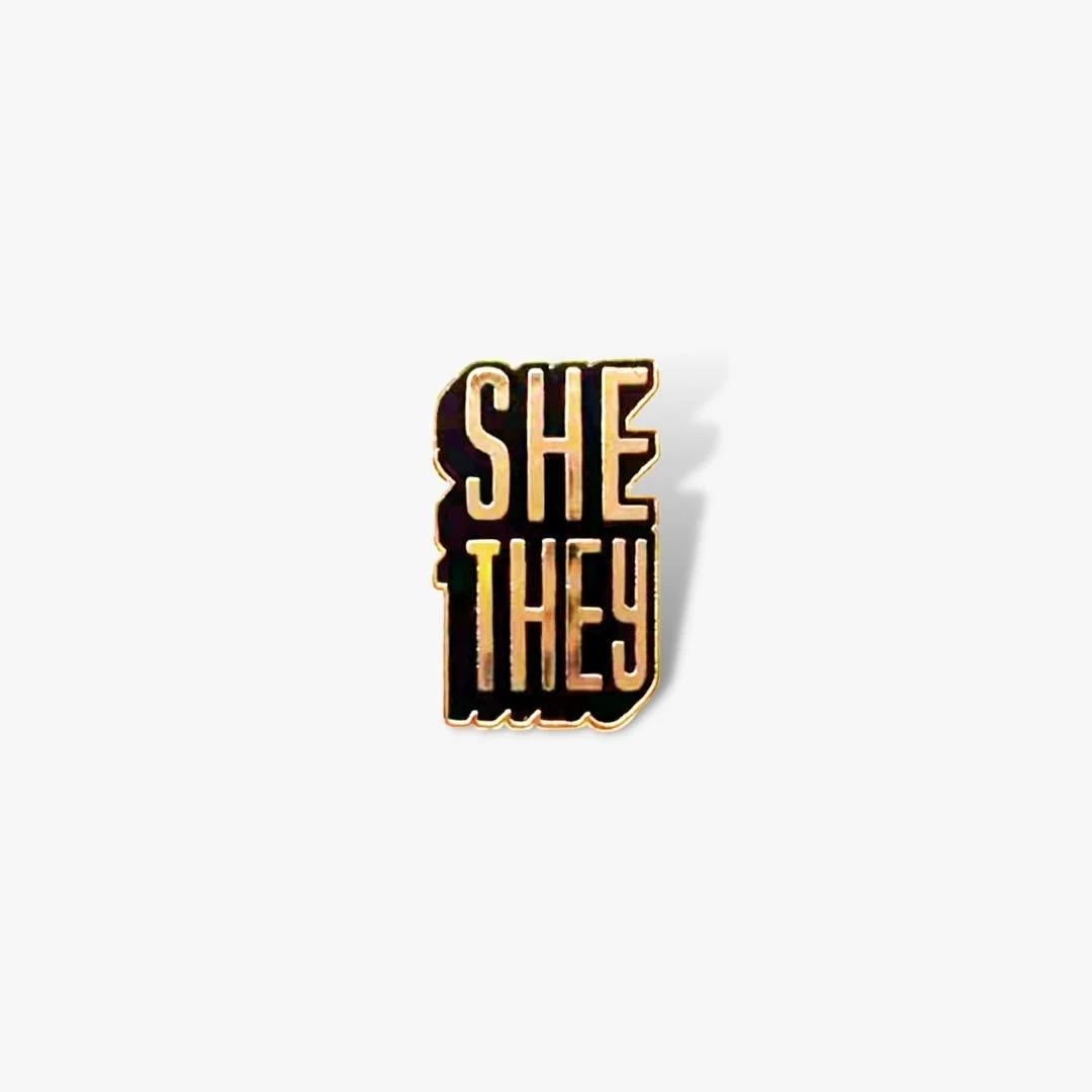Autostraddle New Merch She/They Pronoun Pin 1 Autostraddle New Merch She/They Pronoun Pin